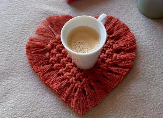 Tasse de café posée sur un coquetier en forme de cœur en macramé.